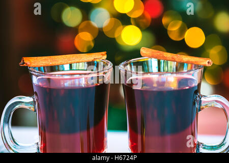 Belle deux verres de vin chaud debout sur l'arrière-plan d'un arbre de Noël décoré brouillée. soft focus dof peu profondes. Banque D'Images