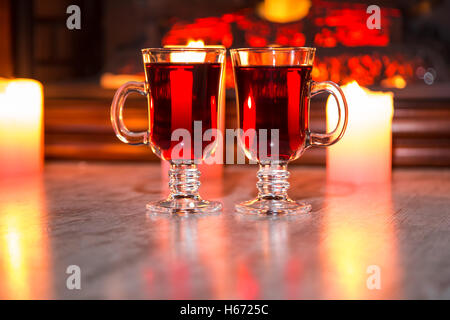 Belle deux verres de vin chaud sur l'arrière-plan flou avec des bougies et une cheminée. L'idée pour les cartes postales. Soft focus. S Banque D'Images