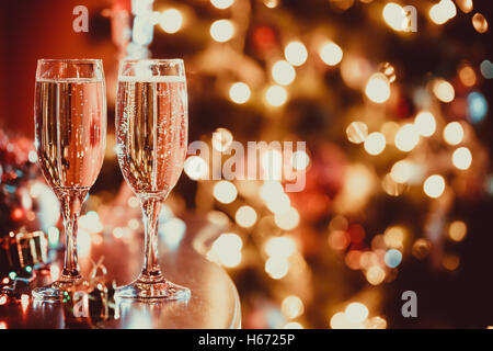 Belle deux verres de champagne debout sur la table en arrière-plan d'une chambre avec un trouble de l'arbre de Noël et décoration Banque D'Images