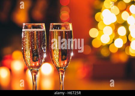 Belle deux verres de champagne debout sur la table en arrière-plan d'une chambre avec un trouble de l'arbre de Noël et décoration Banque D'Images