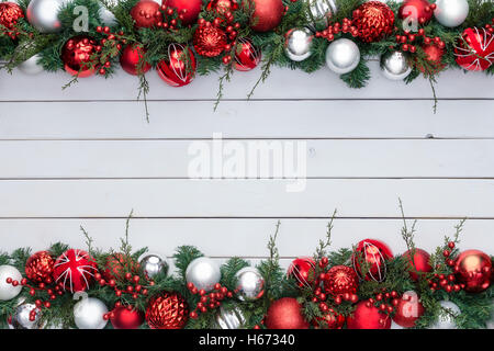 Couleur rouge et blanc double fête Noël frontière avec un assortiment d'ornements d'arbre de noël en vert sur le feuillage du pin staine Banque D'Images