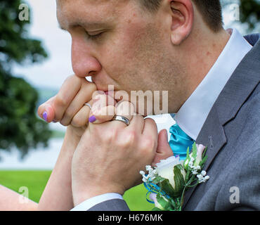 Mari embrassant la main de sa femme le jour de leur mariage Banque D'Images