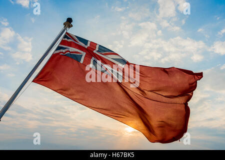 Le 'Red Ensign' flag flying sur le RMS Queen Mary 2 peu avant le coucher du soleil. Banque D'Images