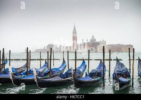 Une rangée de gondoles garé près de la Riva degli Schiavoni à Venise.L'église de San Giorgio Maggiore sur l'île est l'arrière-plan Banque D'Images