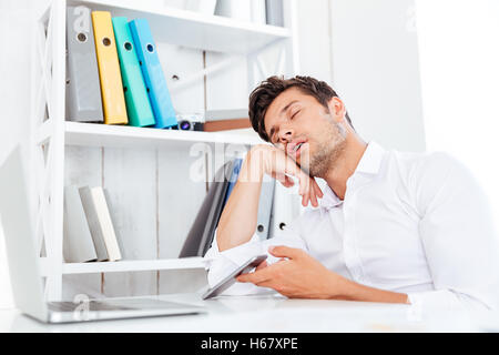 Épuisé de fatigue jeune businessman sleeping assis au bureau 24 Banque D'Images