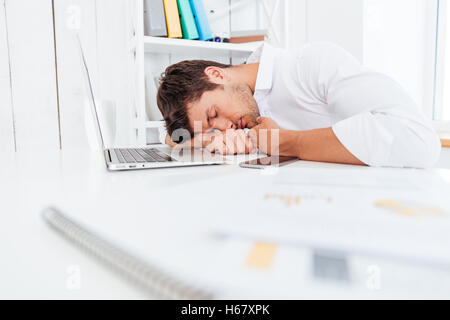 Épuisé de fatigue young businessman dormir sur la table in office Banque D'Images