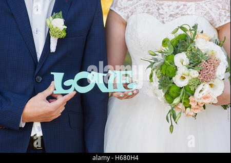 Bride and Groom holding mot amour en bois Banque D'Images