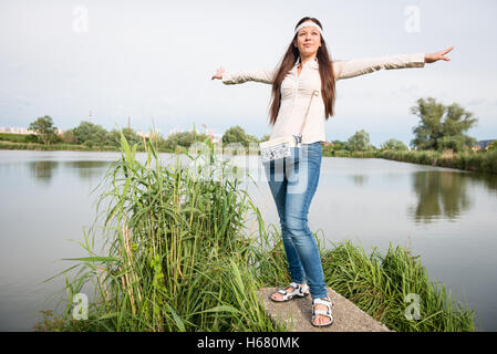 Portrait de jeune dame hippie dans un sac à main jeans avec pose par le lac Banque D'Images