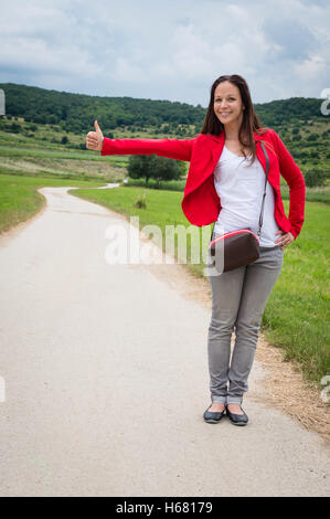 Portrait de jeune dame dans l'auto-stop red jacket par la route Banque D'Images