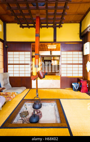 Chambre traditionnelle japonaise dont l'intérieur, portes coulissantes, piscine en contrebas, cheminée irori, pendaison électrique jizaikagi crochet Banque D'Images