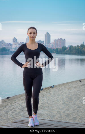 Jeune femme de remise en forme se dresse sur pier la préparation pour des exercices d'entraînement à la fois lever tôt le matin Banque D'Images