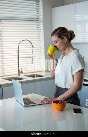 Woman using laptop in kitchen Banque D'Images