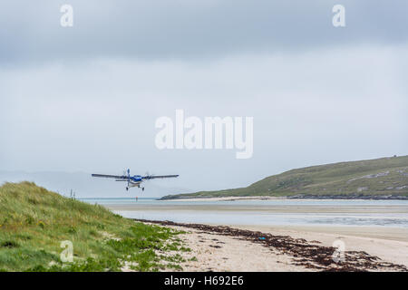 Un vol de Loganair Glasgow terres sur une Tràigh Mhòr (Anglais : La grande plage) qui est utilisé comme une piste. Seulement les avions peuvent atterrir et décoller à marée basse, ce qui signifie que le calendrier varie. Voté l'économie la plus superbe point d'atterrissage, l'aéroport de Barra est le seul aéroport au monde à avoir des vols réguliers sur une plage. Les aéronefs actuellement en opération sur Barra est le de Havilland Canada DHC-6 Twin Otter, piloté par Loganair sur les services à Glasgow. Banque D'Images