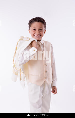 Les jeunes Première Communion boy smiling avec sa veste par-dessus son épaule sur fond blanc Banque D'Images