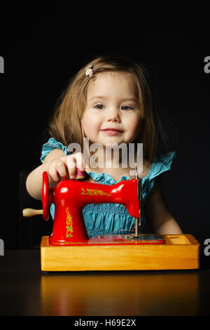 Petite fille joue avec la machine à coudre Banque D'Images