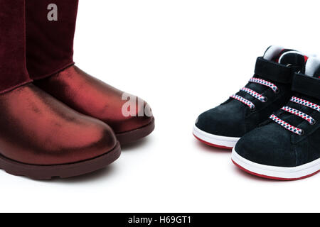 Chaussures noires pour les fils et les rouges pour maman sur le blanc comme concept de la filiation Banque D'Images