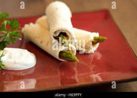 Les asperges roulées dans du pain aplati avec une vinaigrette russe et la crème sure garni de persil Banque D'Images