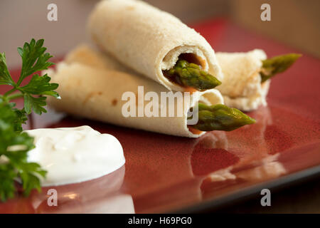 Les asperges roulées dans du pain aplati avec une vinaigrette russe et la crème sure garni de persil Banque D'Images