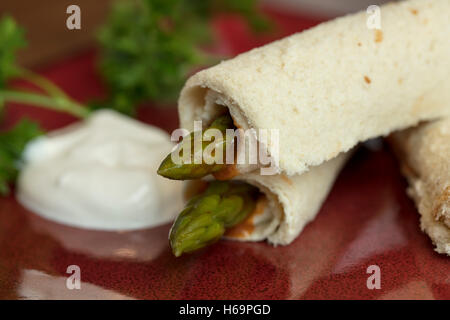 Les asperges roulées dans du pain aplati avec une vinaigrette russe et la crème sure garni de persil Banque D'Images