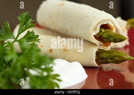 Les asperges roulées dans du pain aplati avec une vinaigrette russe et la crème sure garni de persil Banque D'Images