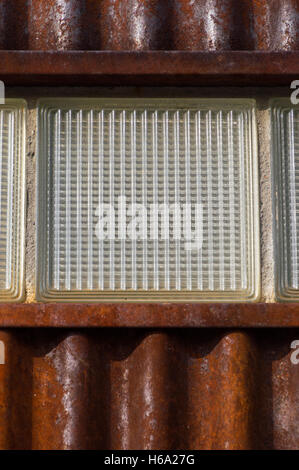 Close Up of Old Rusty, mur de métal ondulé avec une brique de verre texturé Banque D'Images