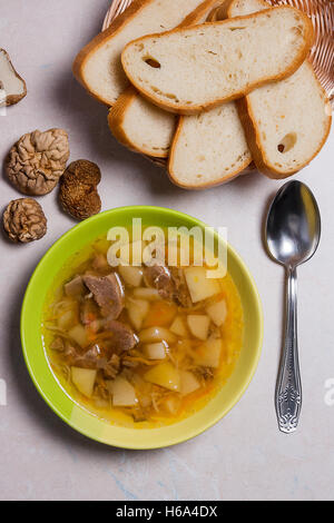 Soupe aux champignons en plaque verte avec cuillère en métal sur un fond noir en lumière. Cèpes séchés plusieurs champignons sauvages ou blanc Banque D'Images