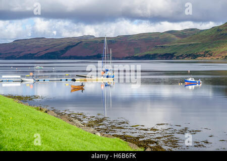 Les bateaux et leurs réflexions sur la belle eaux calmes de Loch Harport à Carbost Île de Skye en Écosse, avec des collines de violet h Banque D'Images