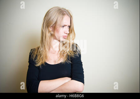 Jeune blonde belle femme à la recherche de son côté, l'expression visage en colère, grincheux, sulky, offensé, maussade Banque D'Images