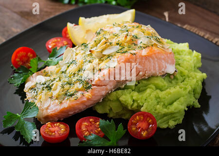 Saumon au four avec du fromage et de la croûte d'amande et garni de purée de pommes de terre et les pois verts Banque D'Images