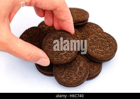 Tambov, Fédération de Russie - le 12 août 2016 Femme hand taking biscuit Oreo de tas d'Oreo sur fond blanc. Banque D'Images