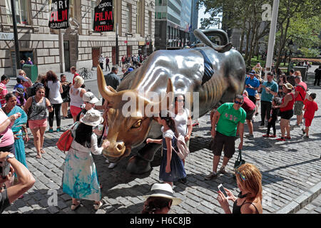 Les touristes autour de la sculpture Bull charge près de Wall Street, New York. Banque D'Images
