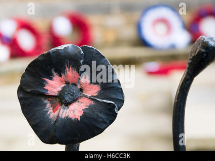 Close up of black garde-corps décoratifs en fer forgé en forme de coquelicot autour d'un mémorial, avec des couronnes de coquelicots derrière Banque D'Images