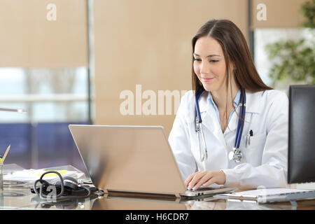 Concentrée sur la ligne médecin travaillant avec un ordinateur portable assis dans un bureau à une consultation. Banque D'Images