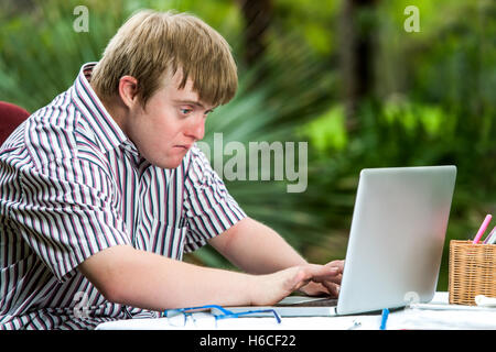 Portrait de jeune homme concentré avec le syndrome de travailler sur un ordinateur portable à l'extérieur. Banque D'Images