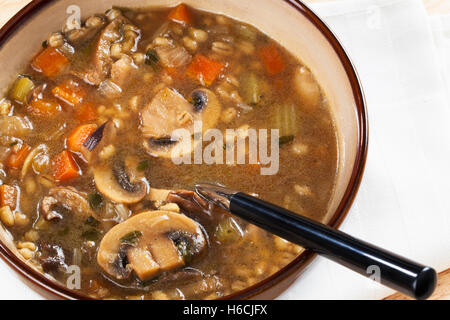 Bol de soupe à l'orge et aux champignons fait maison avec une cuillère d'elle prêt à manger Banque D'Images