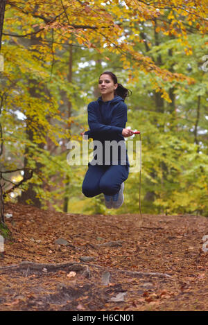 Belle jeune femme fitness corde à sauter dans les forêts, les couleurs de l'automne Banque D'Images