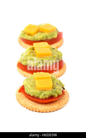 Craquelins à grains entiers avec de la tomate, guacamole et fromage alignés, on white Banque D'Images