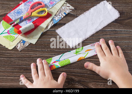 L'enfant plier les bandelettes de tissu. Amulette de protection, textile poupée russe. La couture d'artisanat. Banque D'Images