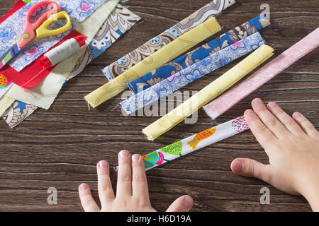 L'enfant plier les bandelettes de tissu. Amulette de protection, textile poupée russe. La couture d'artisanat. Banque D'Images