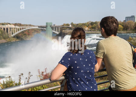 Un couple jouit de la vue sur les chutes américaines et de la rivière Niagara de Luna Island à Niagara Falls, New York. Banque D'Images