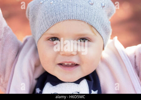 Portrait d'un magnifique sourire tout-petits ; baby girl with hat hiver appréciant jour d'automne dans le parc Banque D'Images