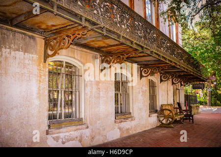 Le long des trottoirs en briques charmant bâtiment historique avec un banc et balcon en fer forgé ornemental au centre-ville de Savannah, GA Banque D'Images