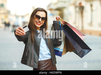 Vente, shopping, tourisme et les gens heureux concept - belle femme avec des sacs de shopping et une carte de crédit dans les mains sur une rue Banque D'Images