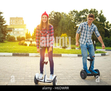 Jeune couple riding scooter électrique - d'hoverboard, eco transport personnel, gyroscope, scooter smart balance wheel Banque D'Images