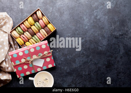 Macarons colorés et petits fruits sur table en pierre. Macarons sucrés et tasse à café. Vue de dessus avec l'exemplaire de l'espace pour votre texte Banque D'Images