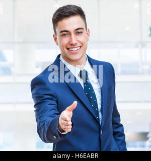 Close up portrait of young attractive Businessman reaching out suite bleue dans la main. Des problèmes de mise au point. Banque D'Images