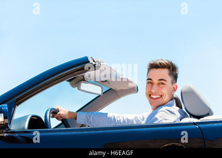 Portrait of handsome young smiling man driving convertible bleu luxueux. Banque D'Images