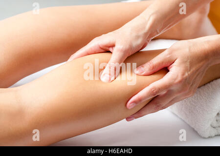 Macro close up of hands en appliquant une pression avec les doigts sur le muscle du mollet. Ostéopathe faire massage sur la guérison de la jambe féminine. Banque D'Images