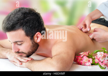 Close up of young man enjoying massage dos. Jeune homme portant la face vers le bas et masser les mains du thérapeute au bas du dos. Banque D'Images