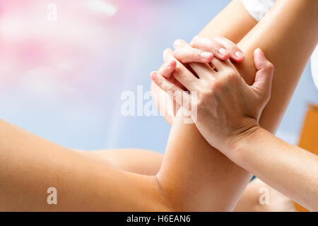 Macro close up d'ostéopathe femme massage musculaire au mollet. Mains manipulation musculaire des jambes inférieures. Banque D'Images